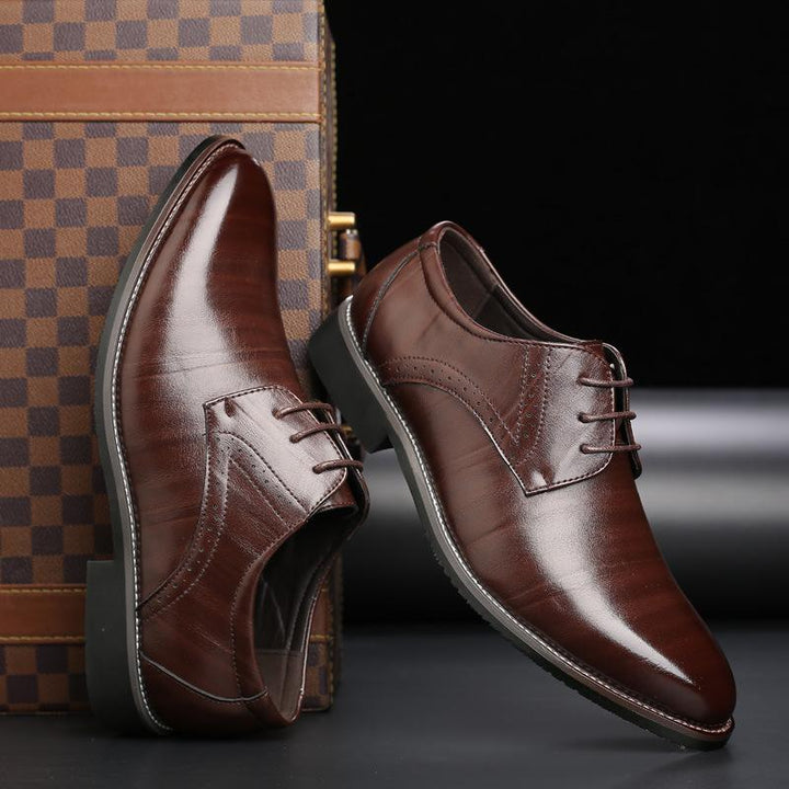 Scarpe eleganti da uomo in pelle marrone lucida, stile derby, su sfondo nero con valigia a scacchi. Calzature formali di lusso.