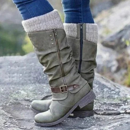 A close-up of a green orthopedic boot with a casual design and knitted cuff, worn by a person standing on rocky ground. The image highlights its stylish appearance and comfort features.